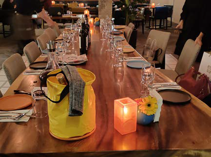 Elegante mesa de restaurante preparada para la cena con velas, servilletas amarillas, copas de vino.