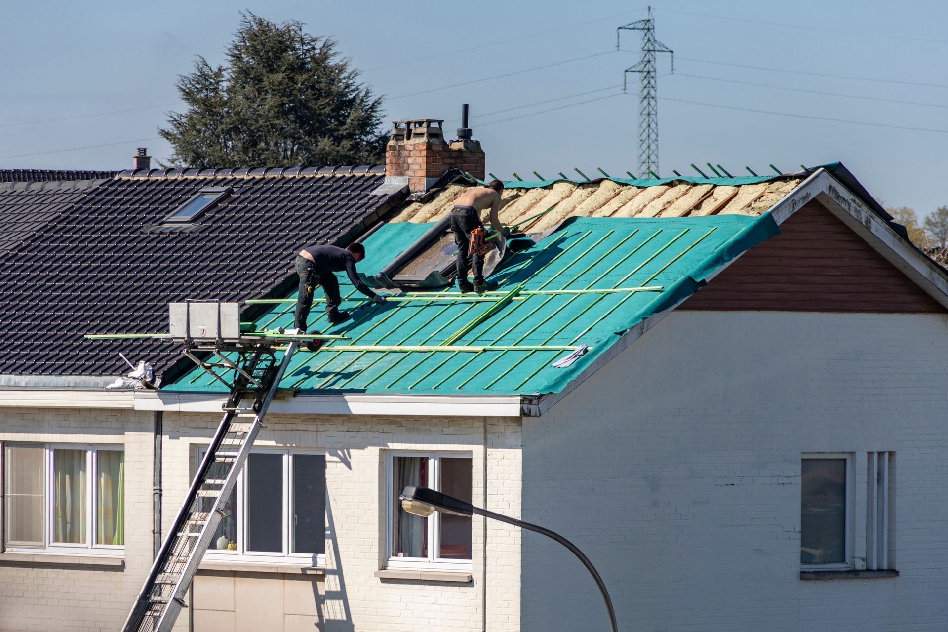 Des ouvriers remplacent le toit d'une maison.