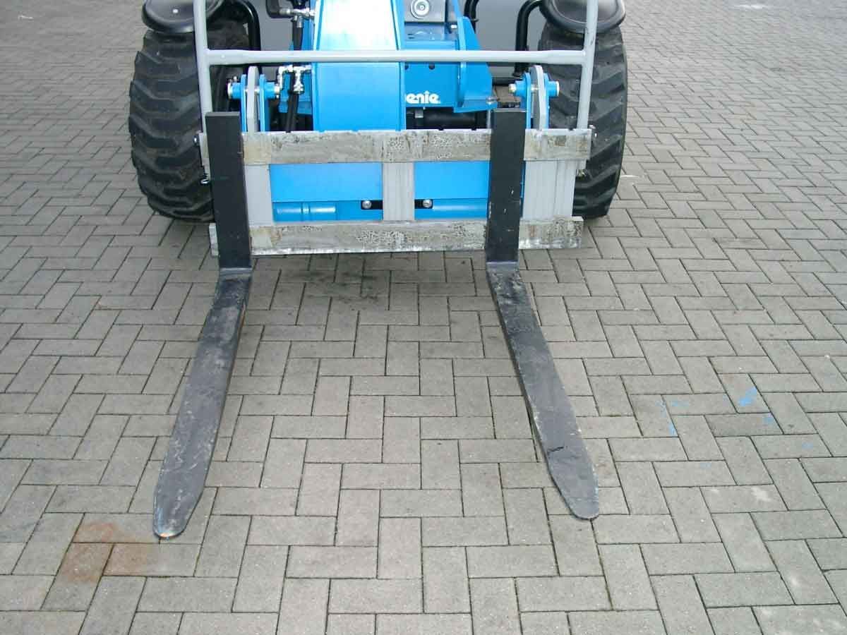 Blauer Gabelstapler mit langen Metallgabeln auf einer gepflasterten Fläche