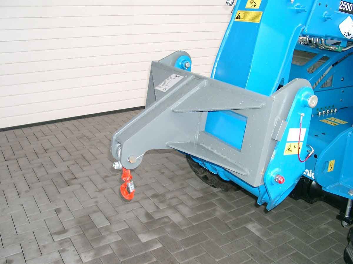 Blaue Industriemaschine mit grauem Schlepparm und orangefarbenem Rad auf einem gepflasterten Boden