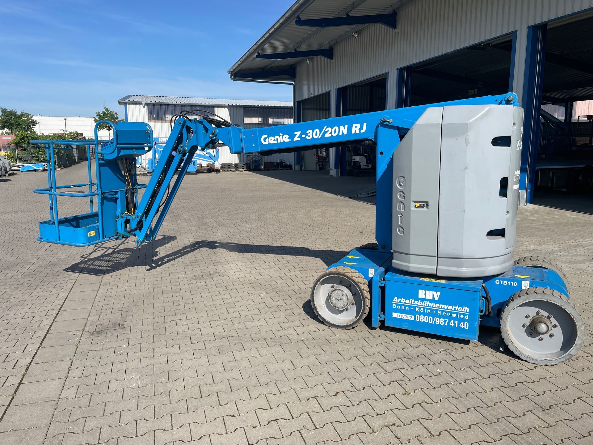 Eine Blue Genie Hubarbeitsbühne ist außerhalb des Ladebereichs eines Lagerhauses geparkt.