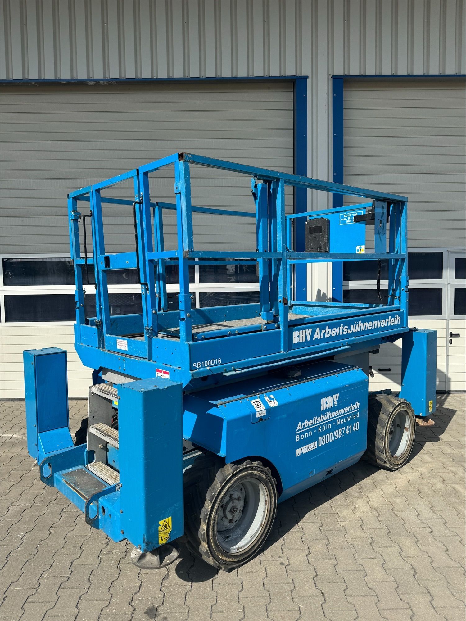 Eine Reihe blauer Scheren- und Hubarbeitsbühnen steht an einem bewölkten Tag im Freien.