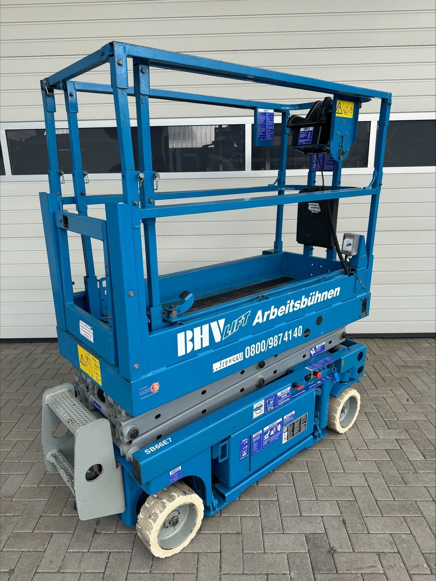 Eine Reihe blauer Scheren- und Hubarbeitsbühnen steht an einem bewölkten Tag im Freien.
