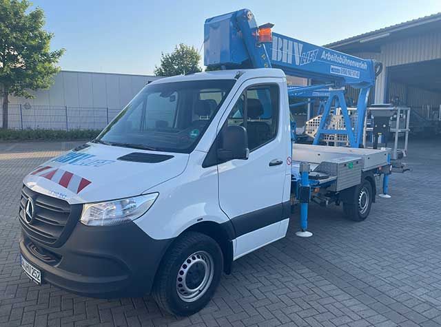 Weißer Lieferwagen mit blauer Hubarbeitsbühne parkt vor einem Gebäude