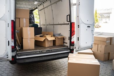 La parte trasera de un camión de reparto está llena de cajas de cartón.
