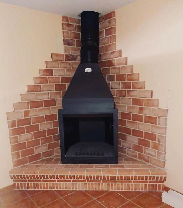 Una chimenea en la esquina de una habitación con ladrillos.
