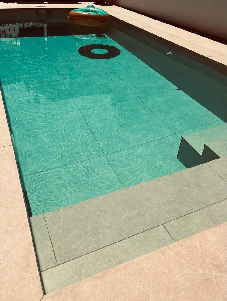 Piscina con agua turquesa, escalera de obra, flotador y hinchable.