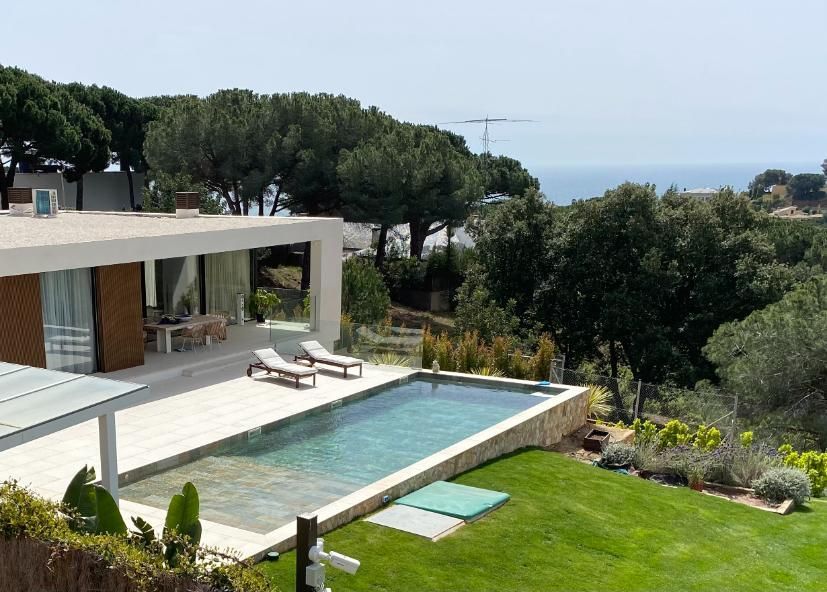 Casa moderna con piscina con vista al mar y paisaje verde con reposeras.