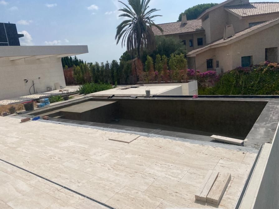 Piscina rectangular vacía en construcción en una azotea, marco de piedra de color claro.