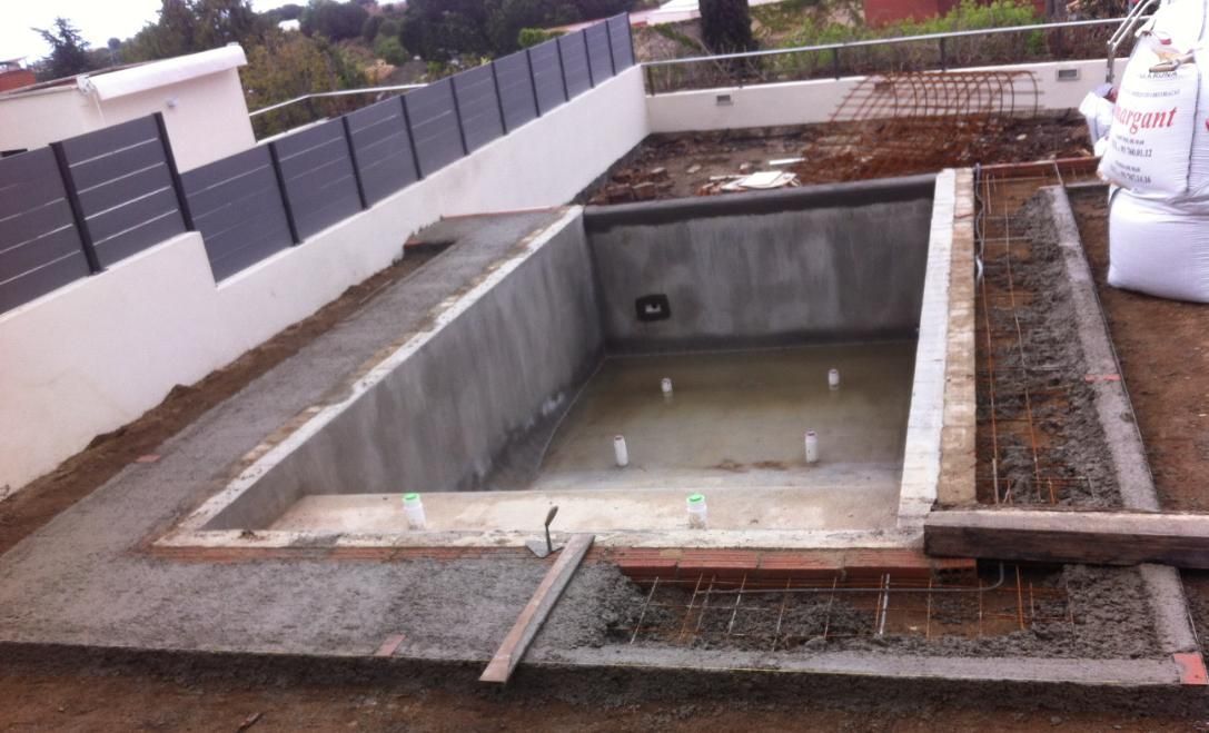 Construcción de una piscina de hormigón; paredes grises, rodeadas de hormigón y varillas de refuerzo,