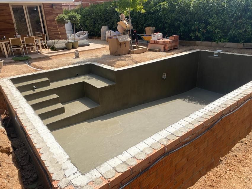 Piscina en construcción, borde de ladrillo, escalones, interior de hormigón. Exterior, soleado.