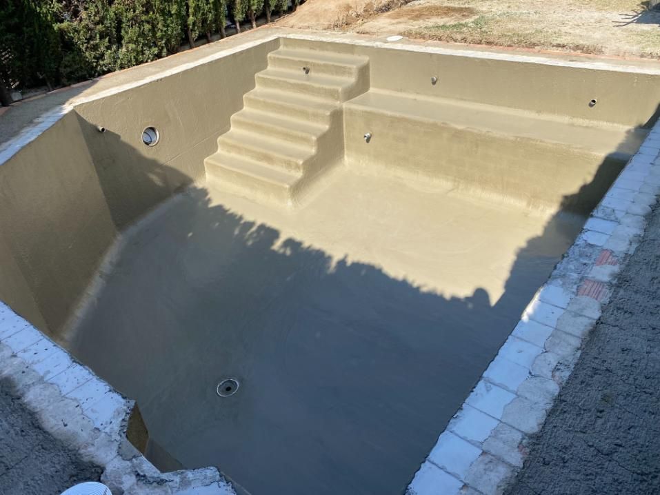 Una piscina rectangular, vacía y recién enlucida, con escalones, vista desde arriba.