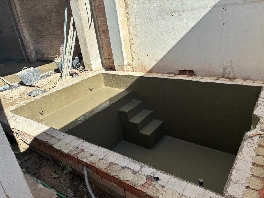 Piscina rectangular de nueva construcción con escalones, paredes sin terminar e interior de hormigón.
