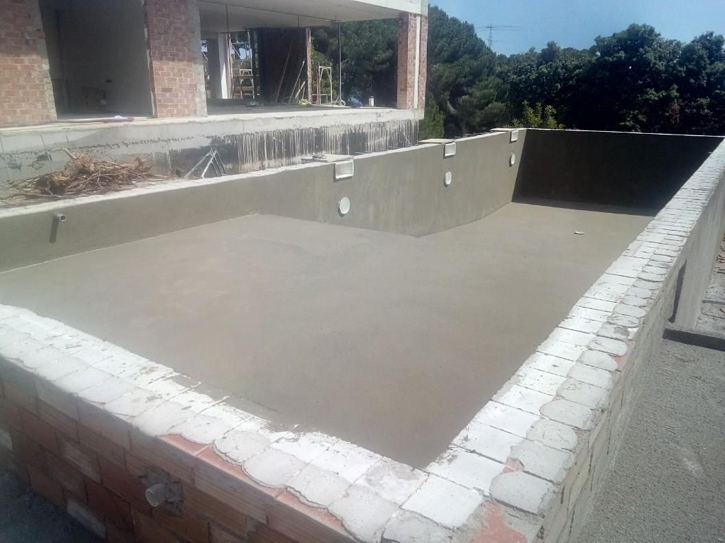 Piscina vacía en construcción con paredes de ladrillo y cemento.