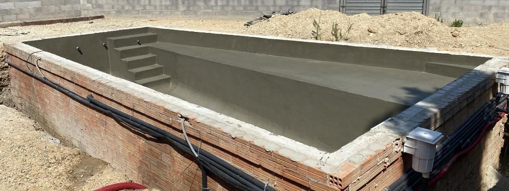 Una piscina vacía, rectangular y enterrada en construcción.
