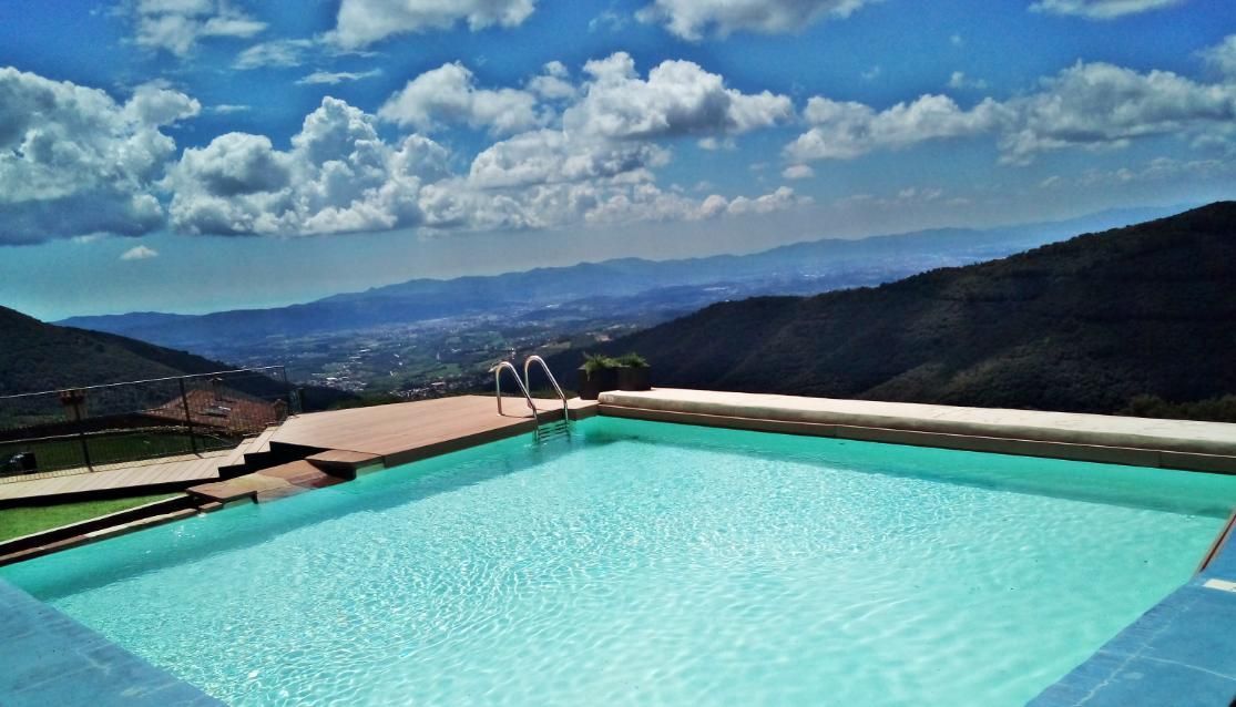 Piscina con vistas a un paisaje montañoso bajo un cielo parcialmente nublado.