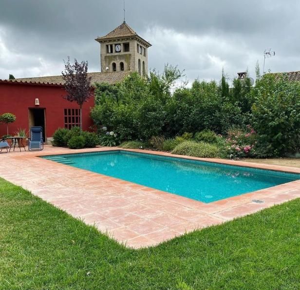 Una piscina rectangular con borde de ladrillo en un patio trasero. 