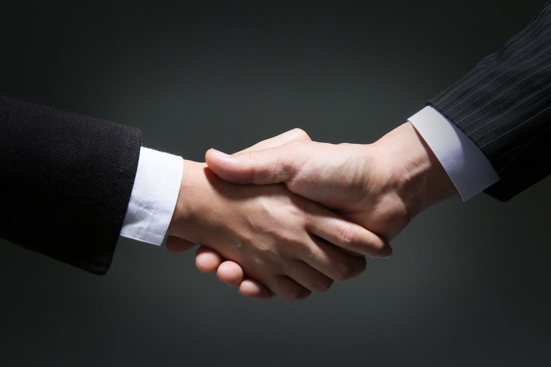 Zwei Männer geben sich in einem dunklen Raum die Hand.