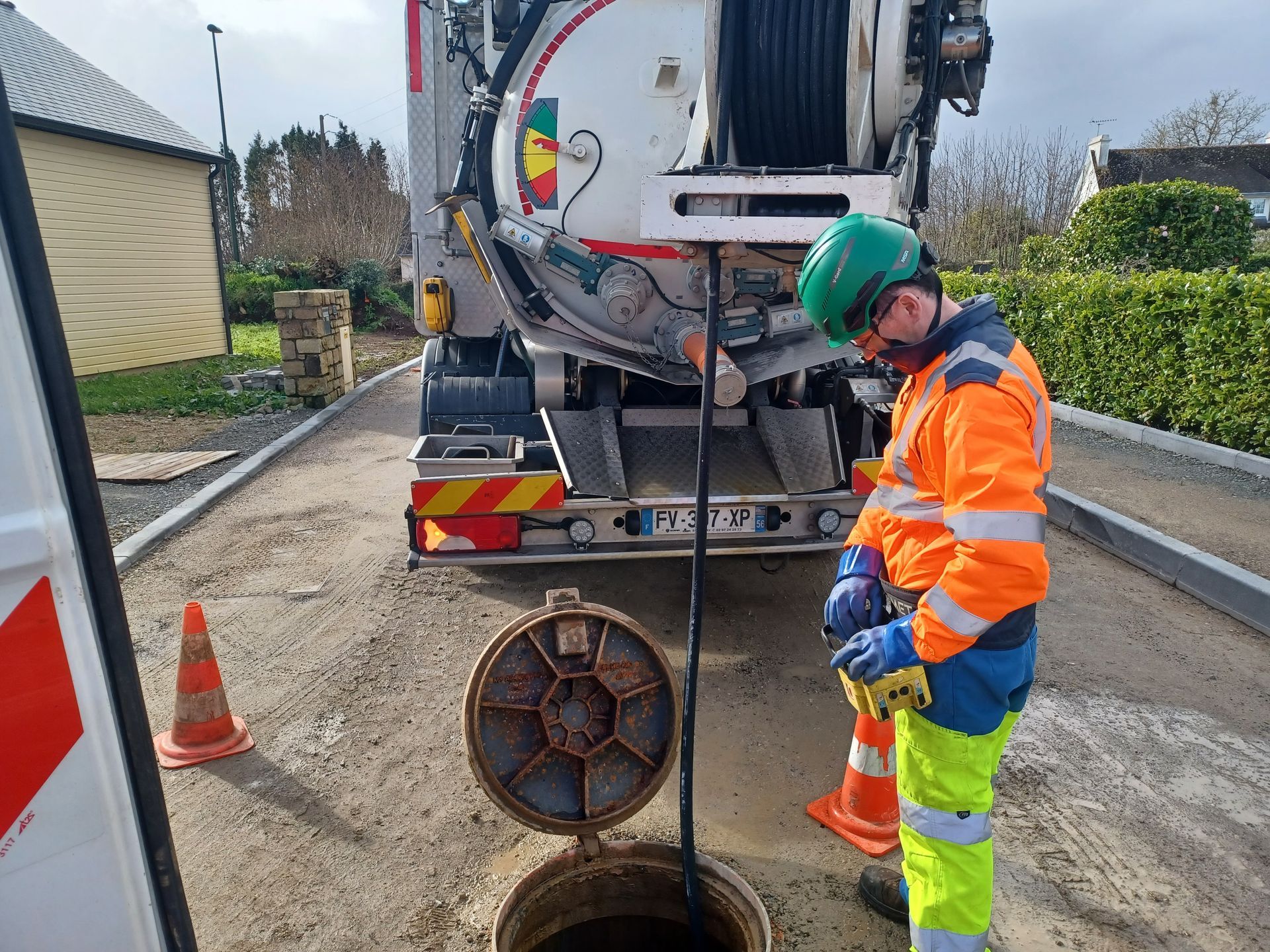Un technicien à côté d'une bouche d'égoût.
