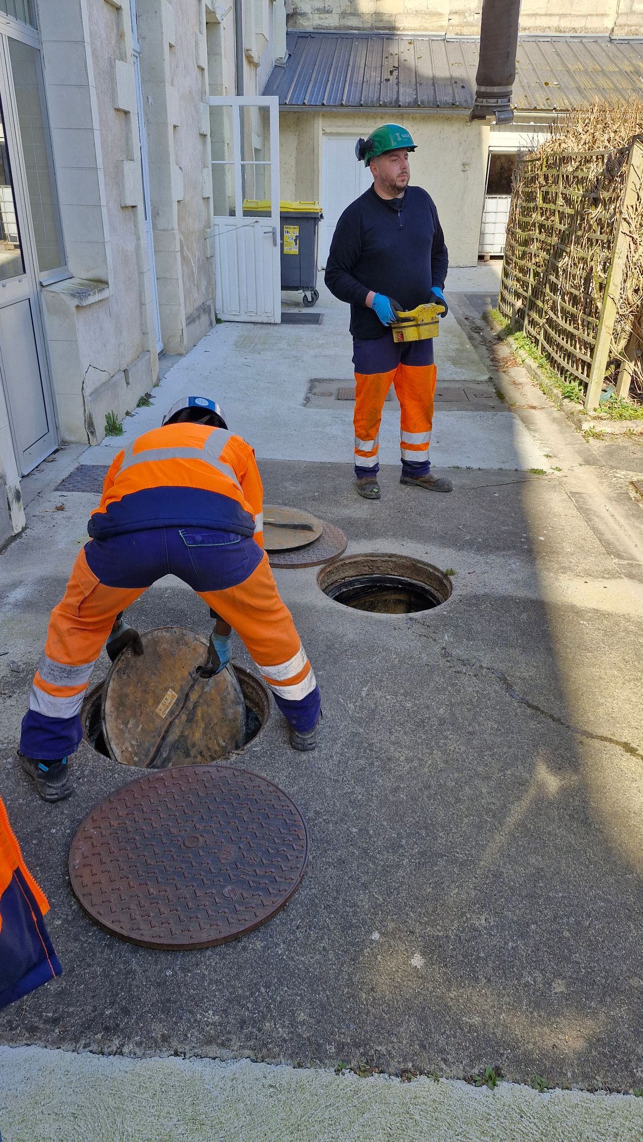 Deux techniciens et deux bouches d'égout.