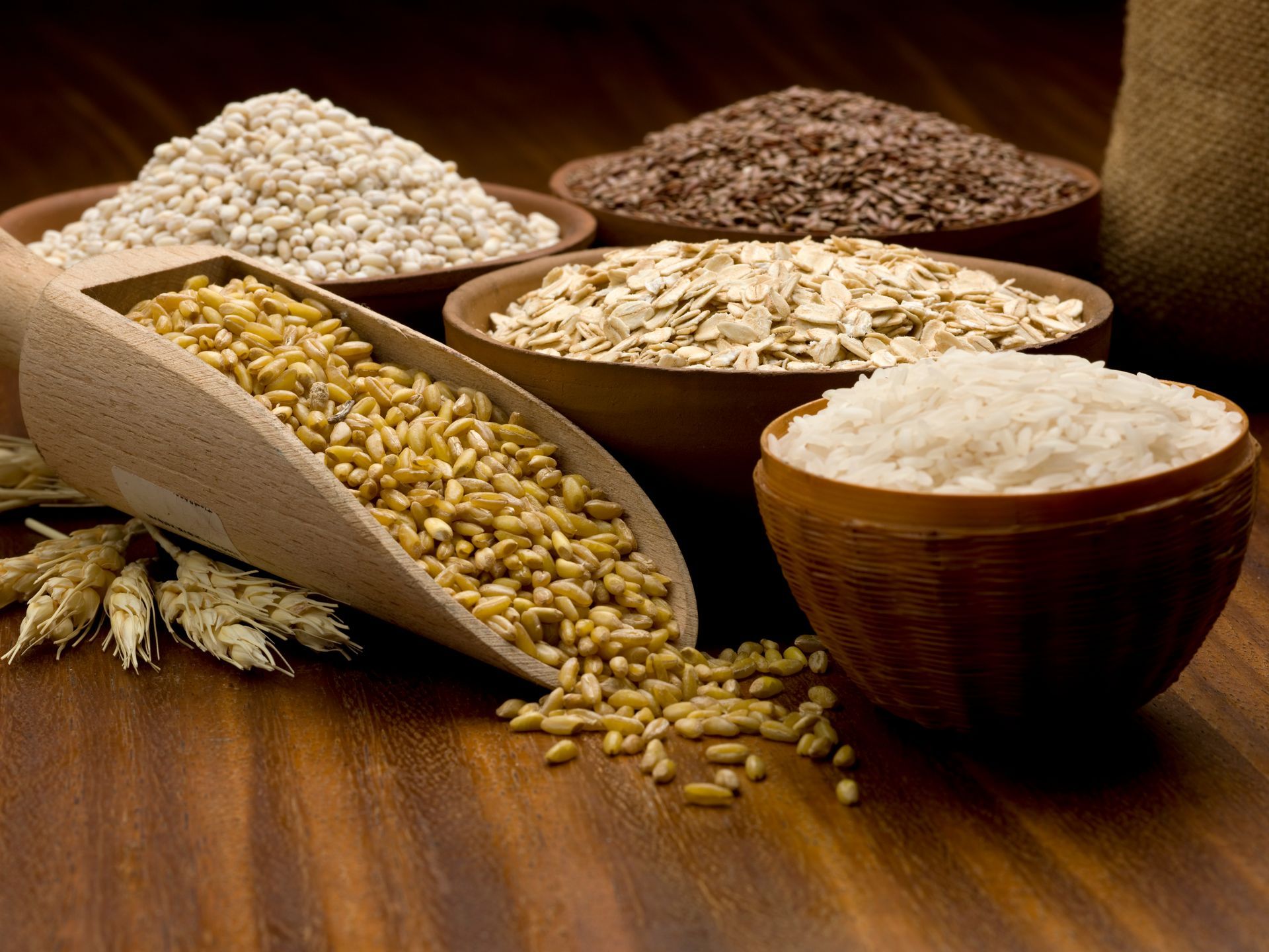 Una mesa de madera cubierta con cuencos de diferentes tipos de granos.