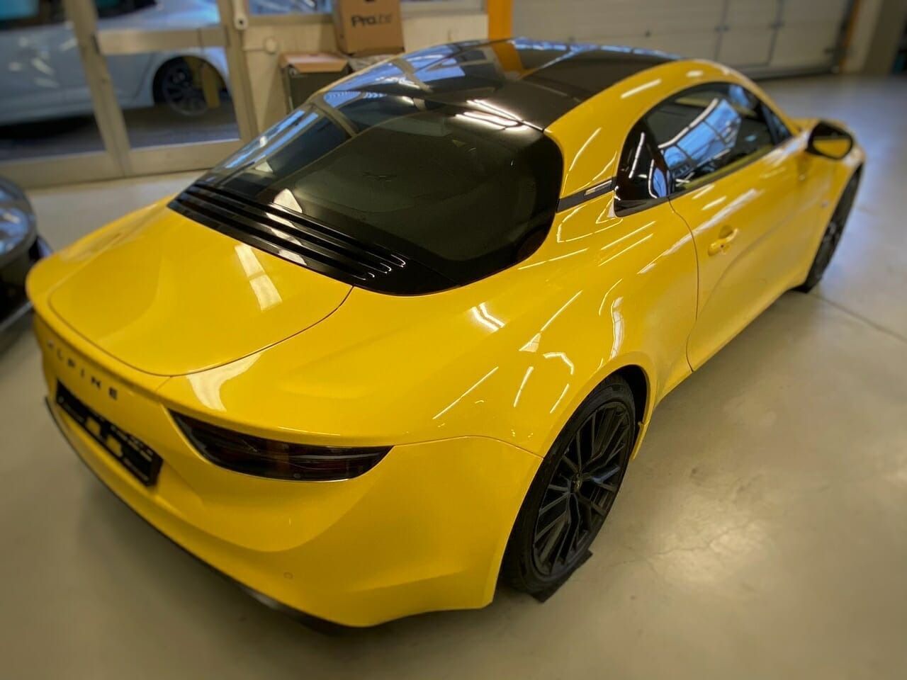 Ein weisser Renault Megane Schrägheckwagen mit roten Leichtmetallfelgen, geparkt im Freien auf einem gepflasterten Parkplatz.