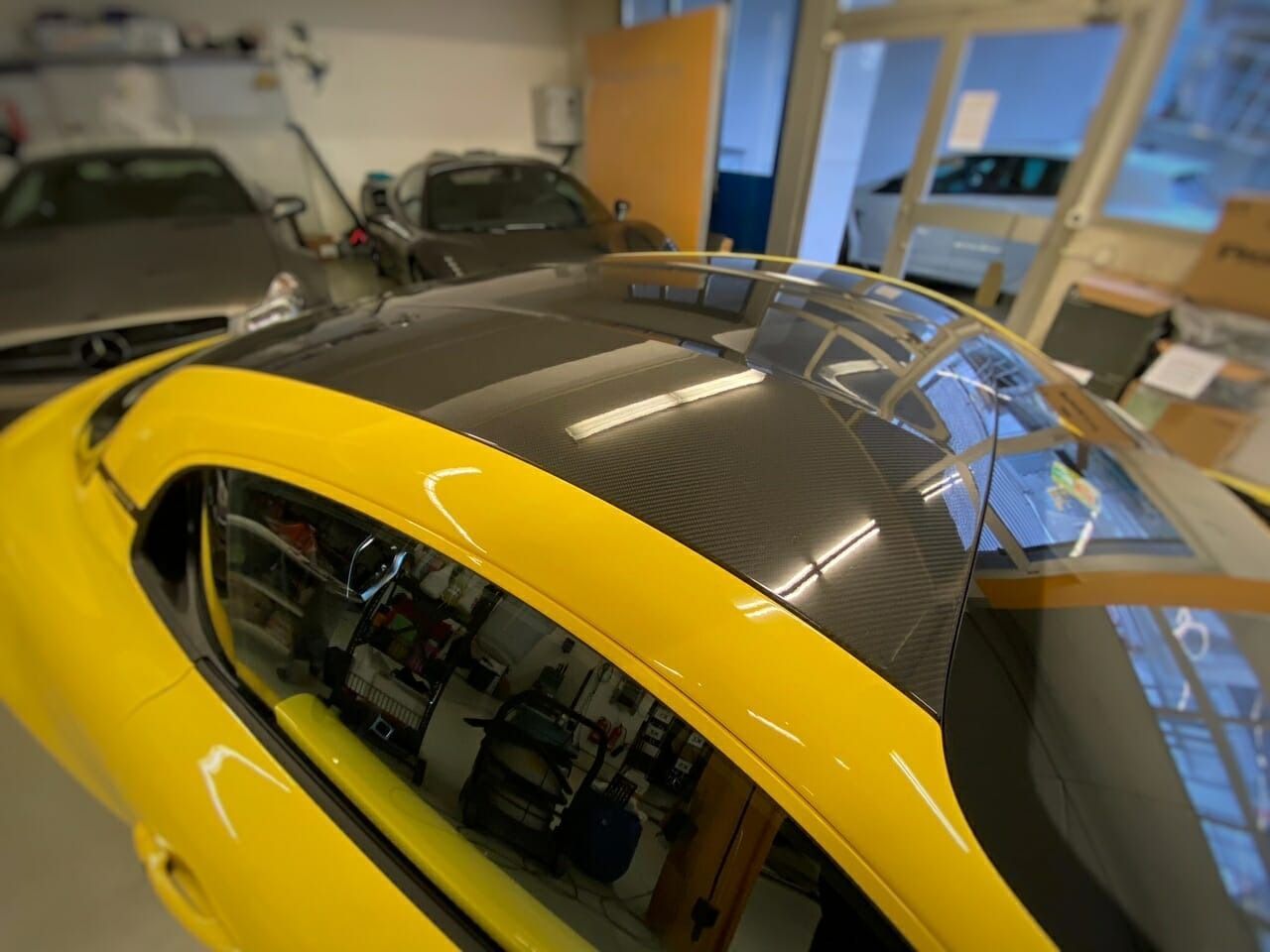 Ein weisses Auto mit leuchtend roten Spezialfelgen, geparkt auf einem gepflasterten Platz im Freien.