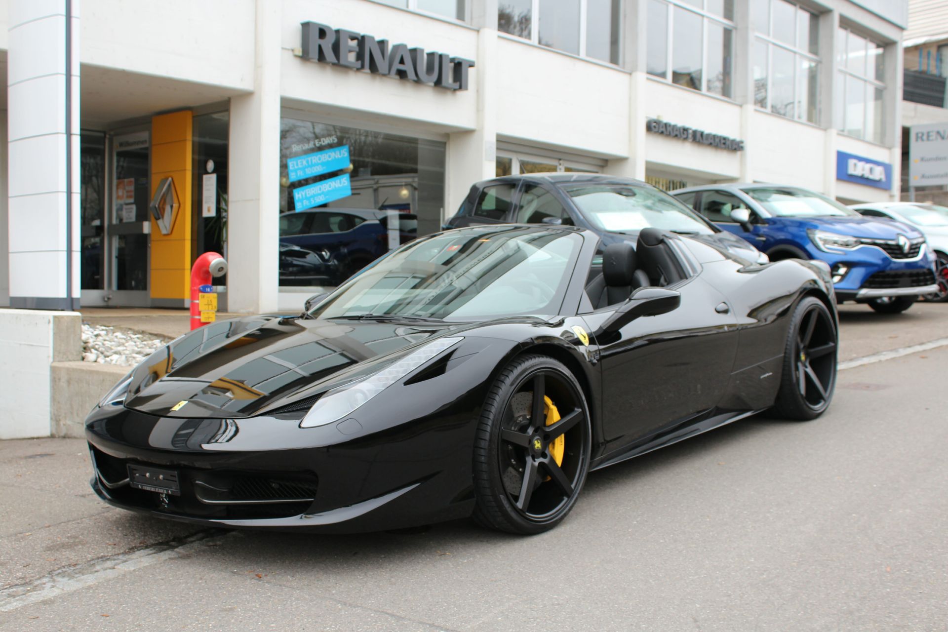 Ein schwarzer Ferrari Sportwagen parkt vor dem Autohaus Garage Klarer