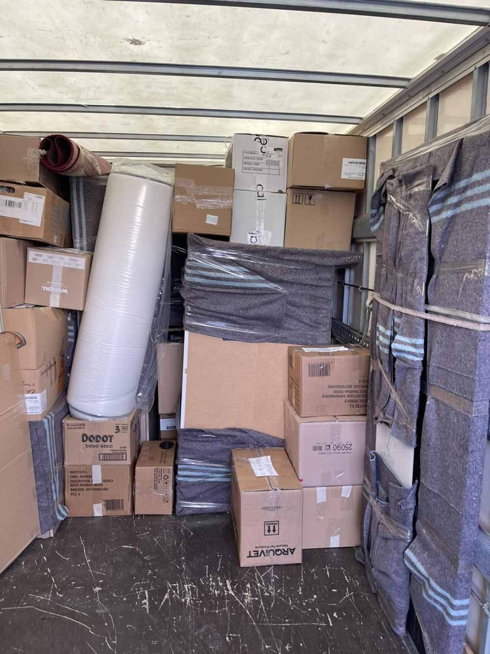 El interior de un camión de mudanzas lleno de cajas y un colchón.