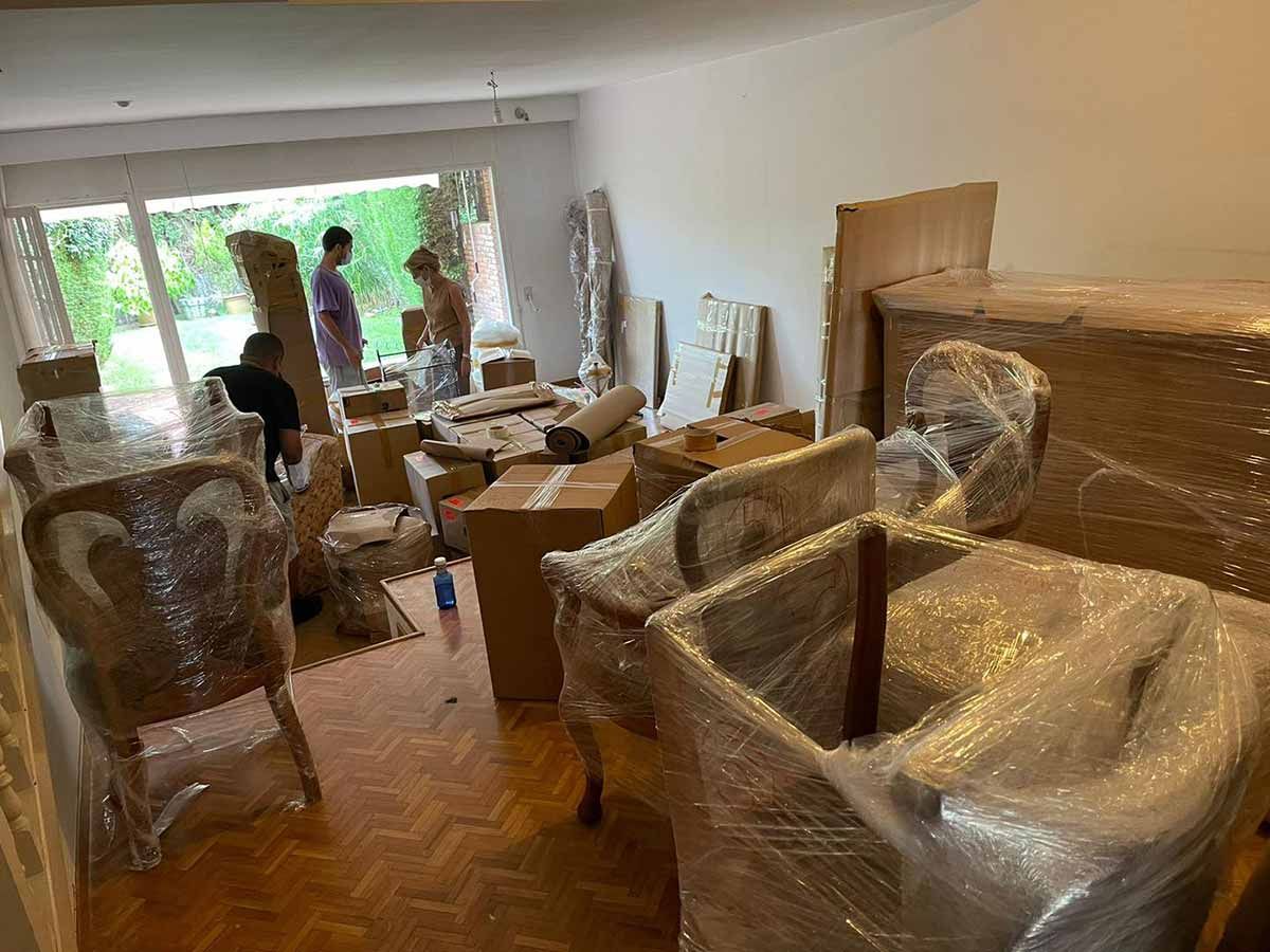 Una habitación llena de muchas cajas y sillas envueltas en plástico.