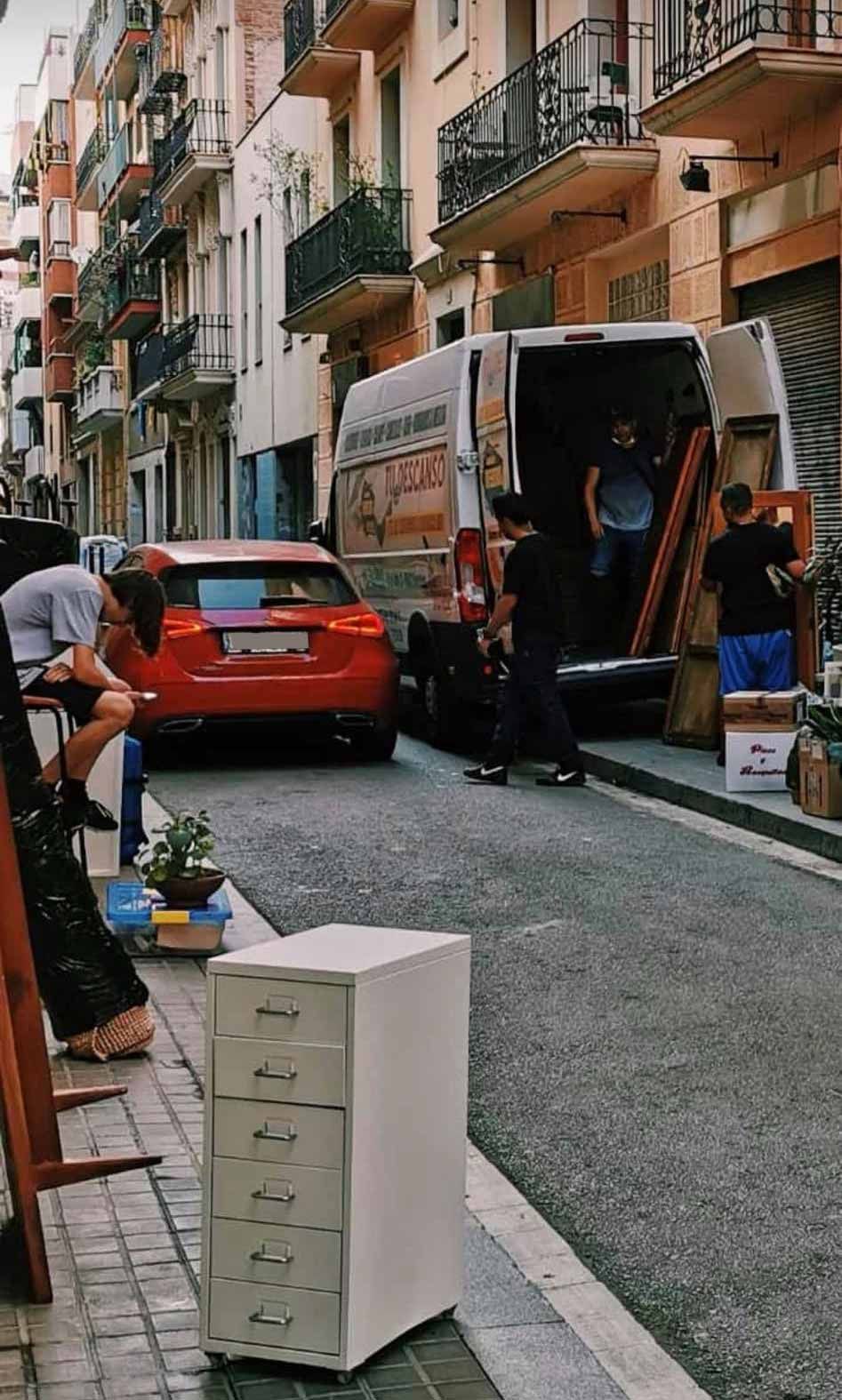 Un coche rojo está aparcado al costado de la carretera al lado de una camioneta.
