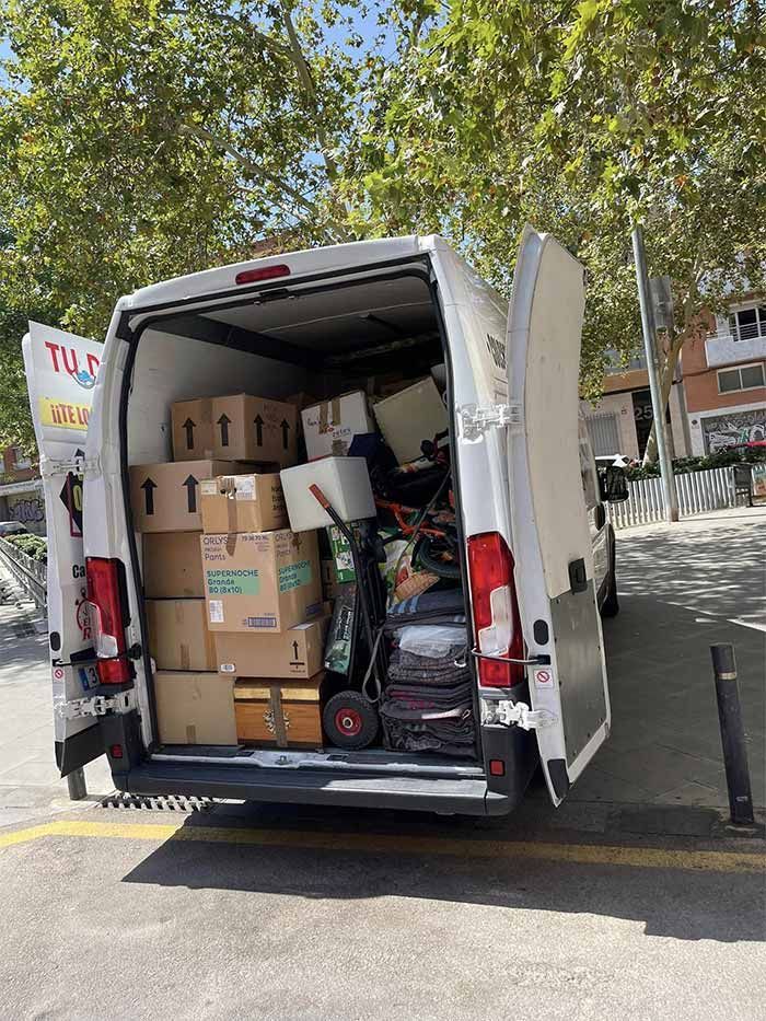 Una camioneta blanca llena de cajas y equipaje está estacionada al costado de la carretera.