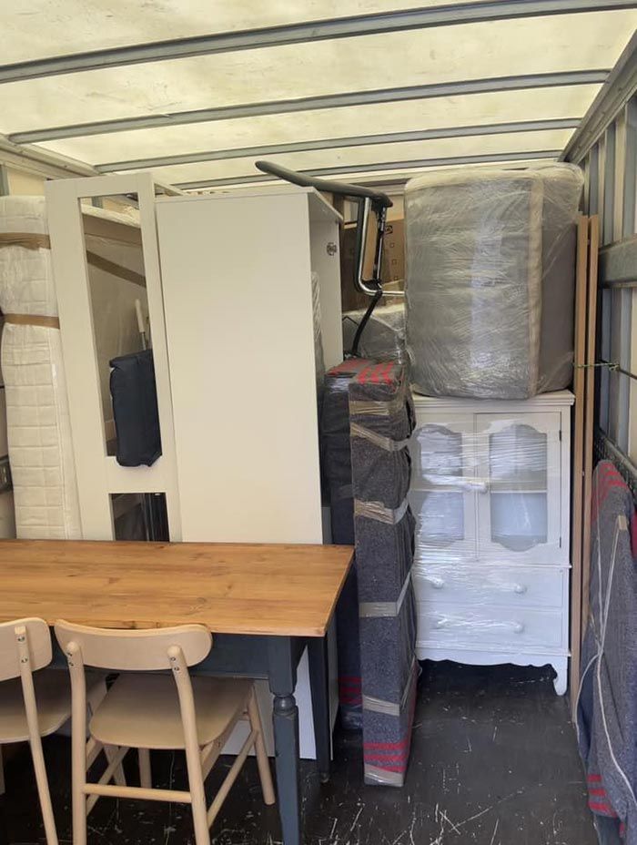 Un camión de mudanzas lleno de muebles, incluida una mesa y sillas.
