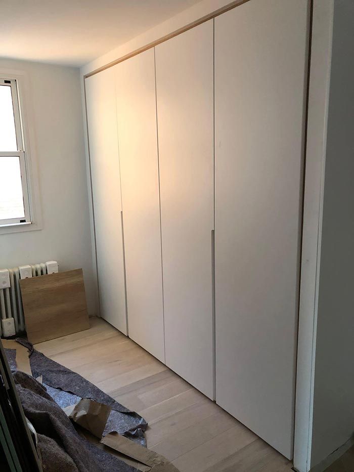 Una habitación con muchos armarios blancos y una ventana.