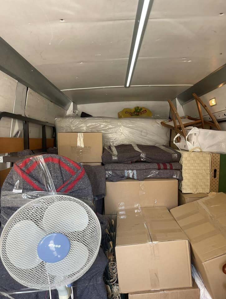 El interior de un camión de mudanzas lleno de cajas y un ventilador.