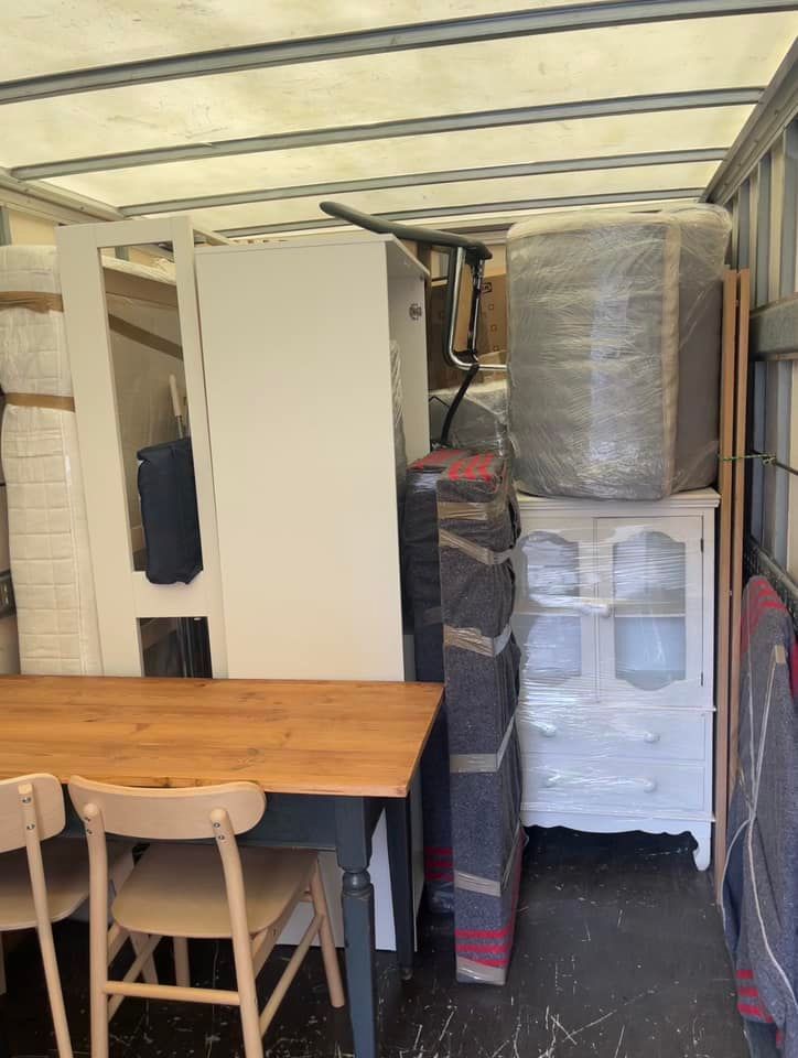 Un camión de mudanzas lleno de muebles, incluida una mesa y sillas.