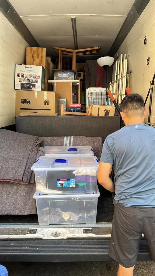 Un hombre está cargando cajas en la parte trasera de un camión de mudanzas.