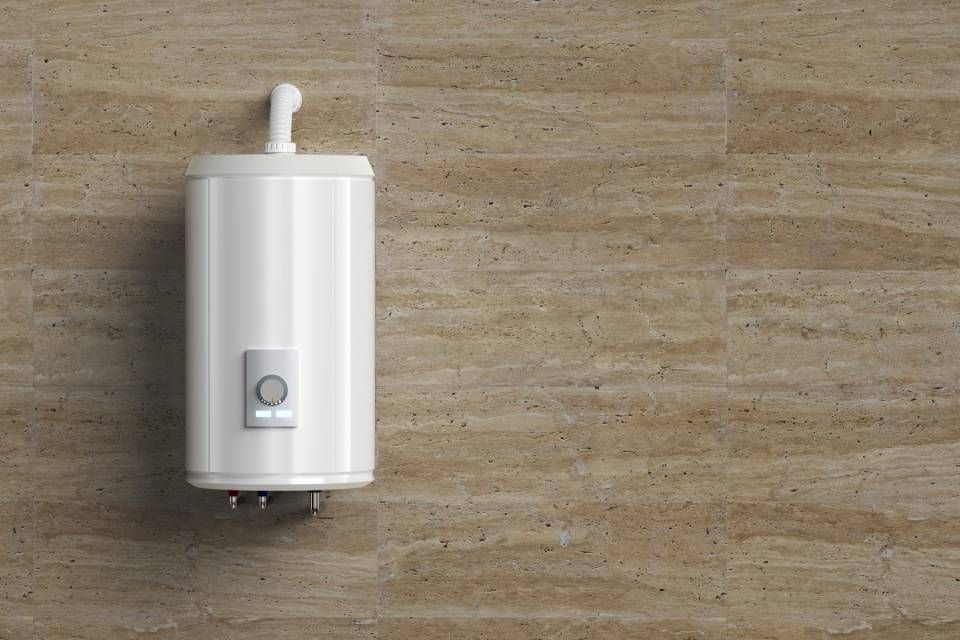 Un chauffe-eau blanc est accroché sur un mur carrelé.