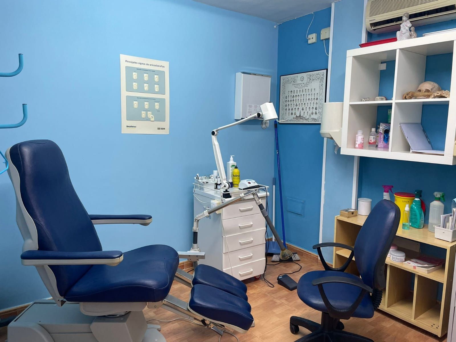 Consultorio de podología, paredes azules, silla azul, equipamiento médico, oficina pequeña.