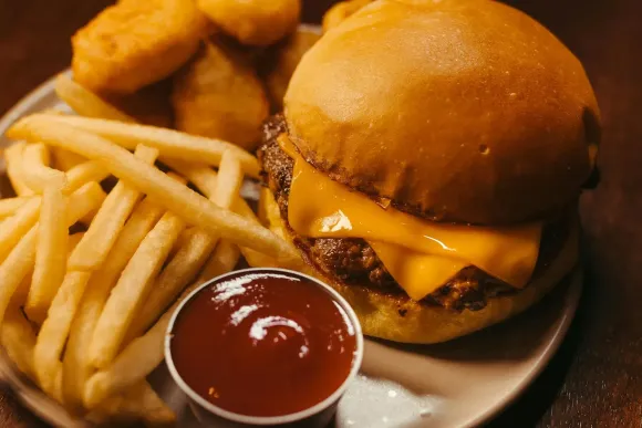 Hamburguesa con queso en pan, patatas fritas, nuggets y ketchup en un plato.