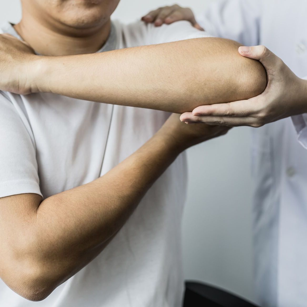 Un médico examina el codo de un hombre.