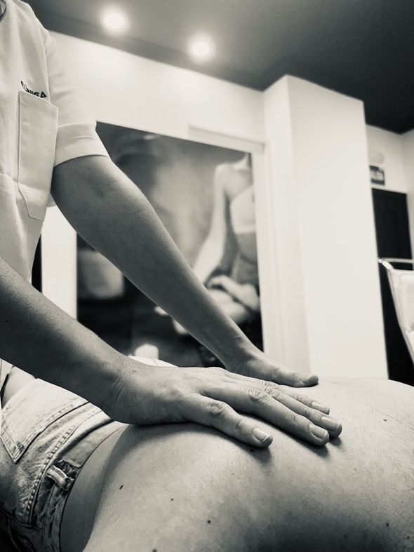 Un hombre le está dando un masaje a una mujer en la pierna.