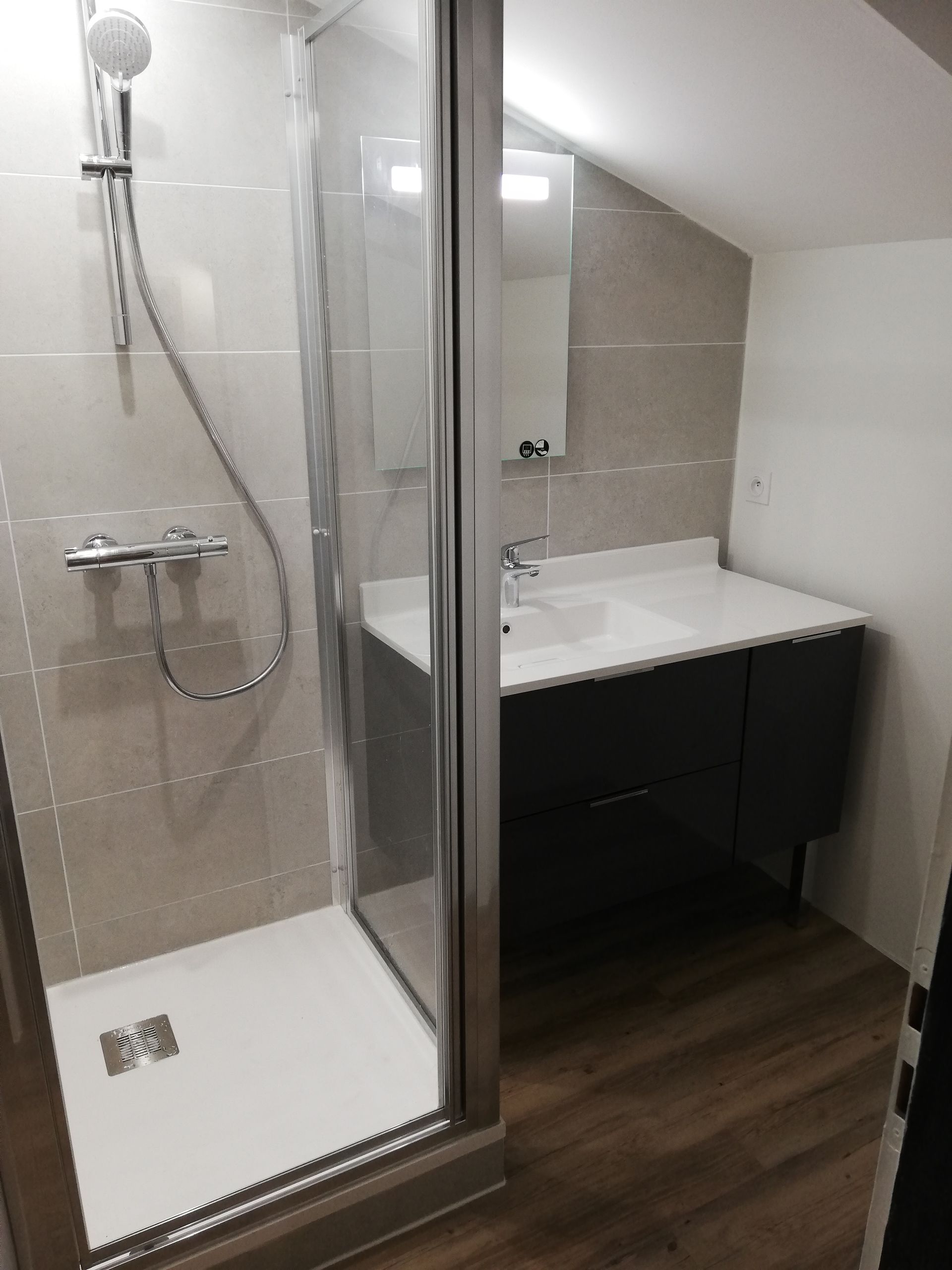 Salle de bains rénovée avec douche et mobilier noir