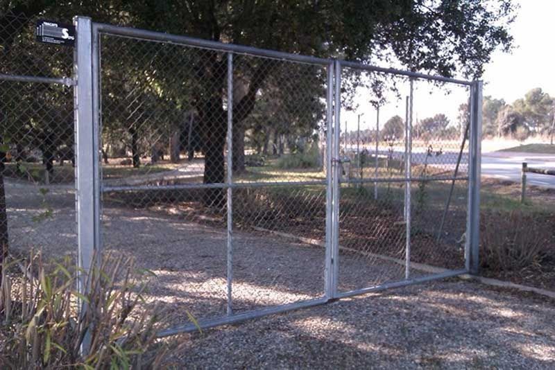 Una valla de alambre con árboles al fondo