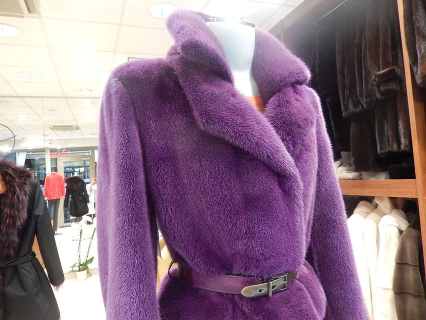 Manteau duveteux violet avec ceinture assortie présenté sur un portant de vêtements