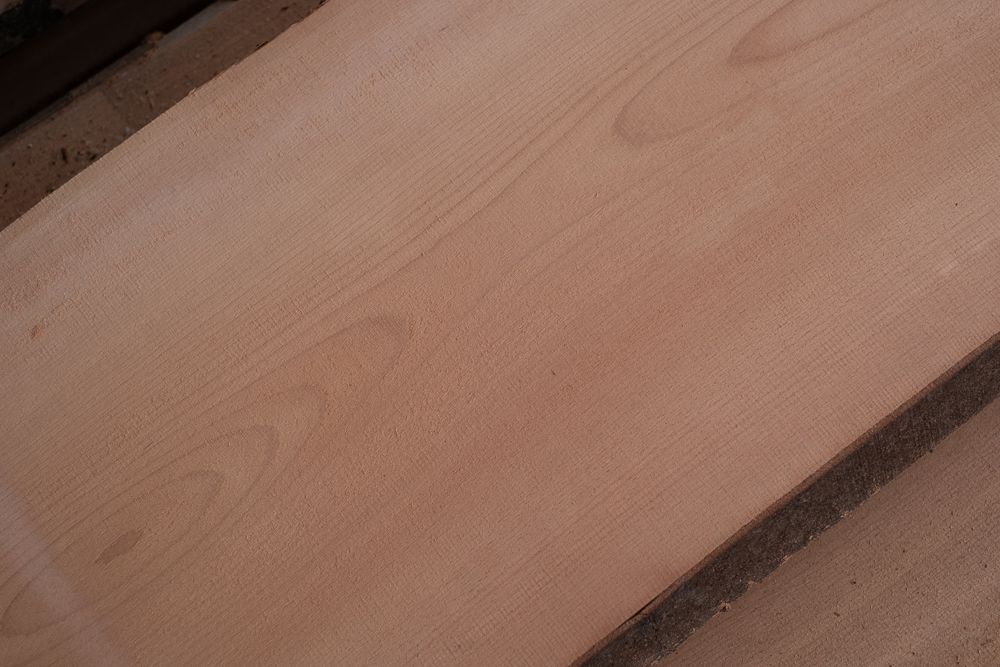 Nahaufnahme eines hellbraunen Holzbretts, das die Maserung und Struktur des Holzes zeigt.