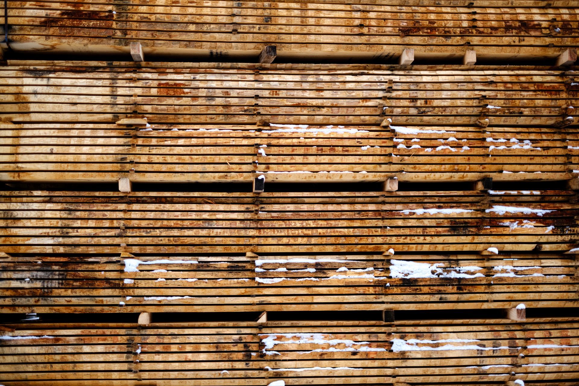 Stapel verwitterter Holzbretter mit horizontalen Linien und verschiedenen Brauntönen.