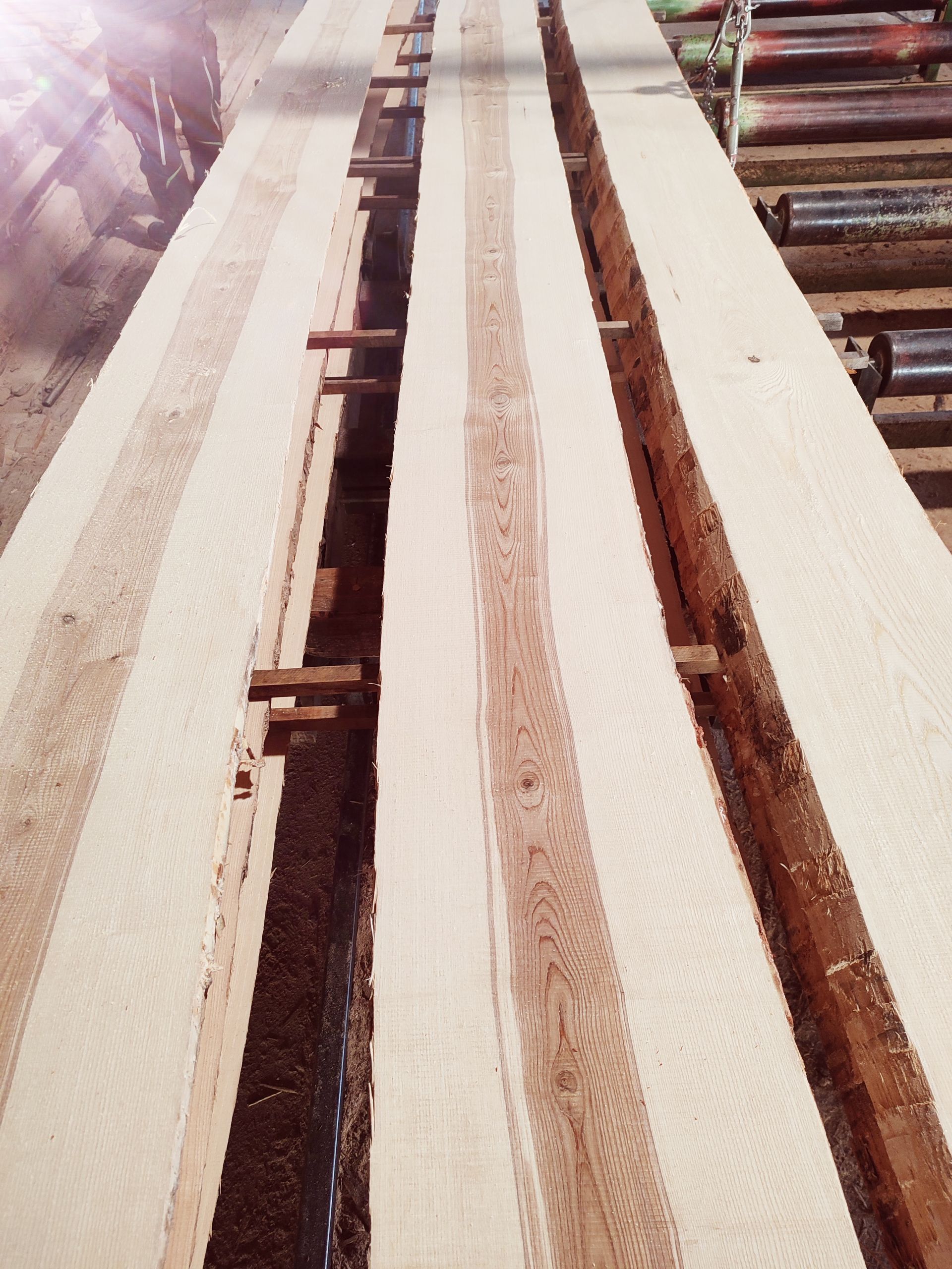 In einem Sägewerk gestapelte Holzbretter, gesichert mit Holzstützen.