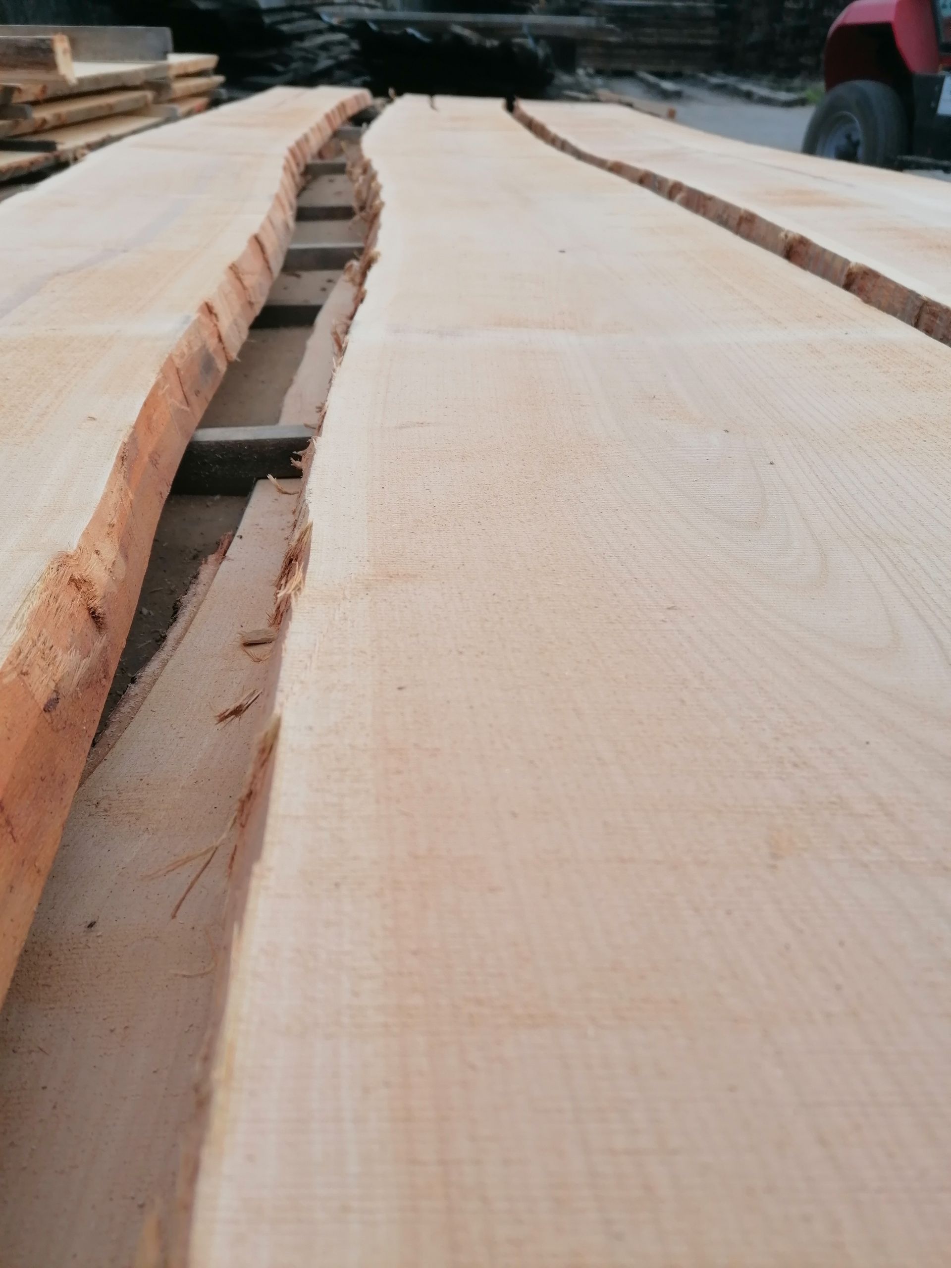 Holzbretter mit Naturkanten, im Freien gestapelt, hellbraun.