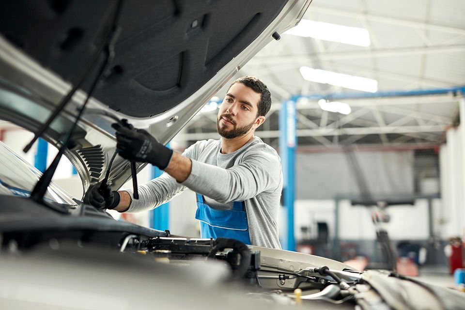 Garagiste qui soulève le capot d'une voiture